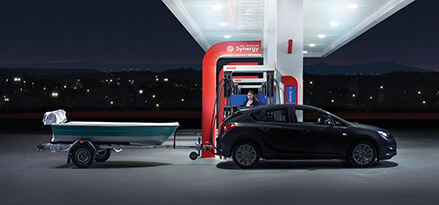 Eine Frau betankt ihr schwarzes Auto mit Bootsanhänger an einer Esso Tankstelle.